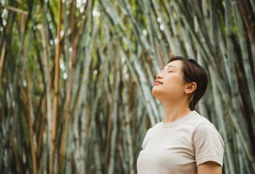 woman relaxing and breathing in fresh air in a bamboo forest